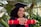 A smiling graduate holding their diploma in a celebratory atmosphere.