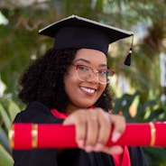 smiling woman wearing academic dress and black academic hat by Felipe Gregate (https://unsplash.com/@felipegregate)