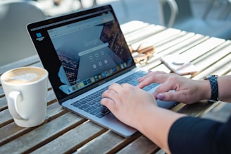 person using macbook pro on brown wooden table