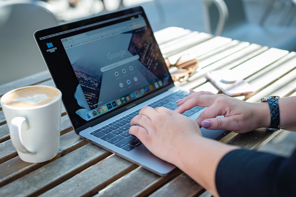 person using macbook pro on brown wooden table