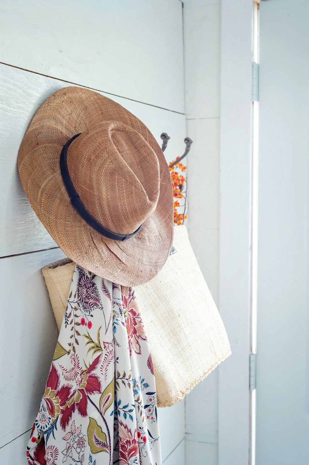 brown fedora hat on white and red floral textile