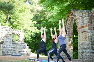 3 women doing yoga in an outdoor setting