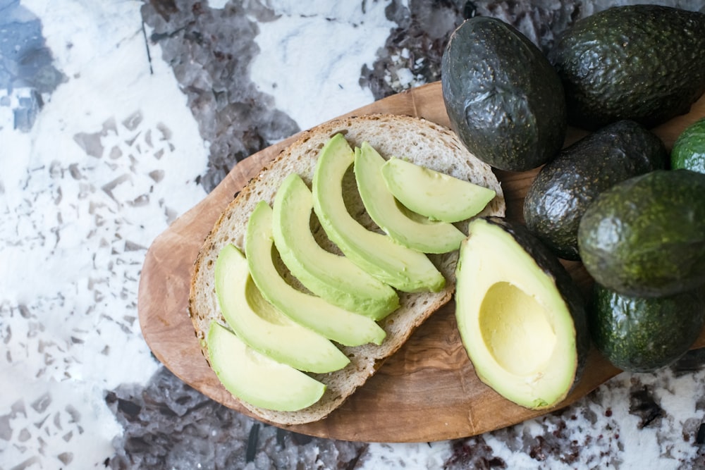 geschnittene Avocadofrüchte auf braunem Holzschneidebrett