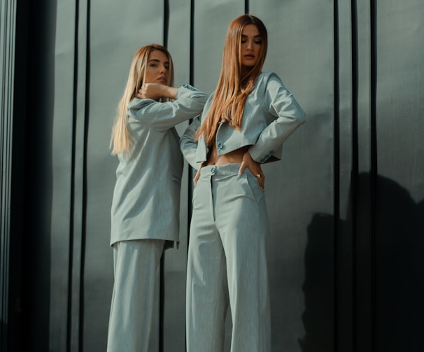 2 women in white long sleeve shirt standing beside glass window