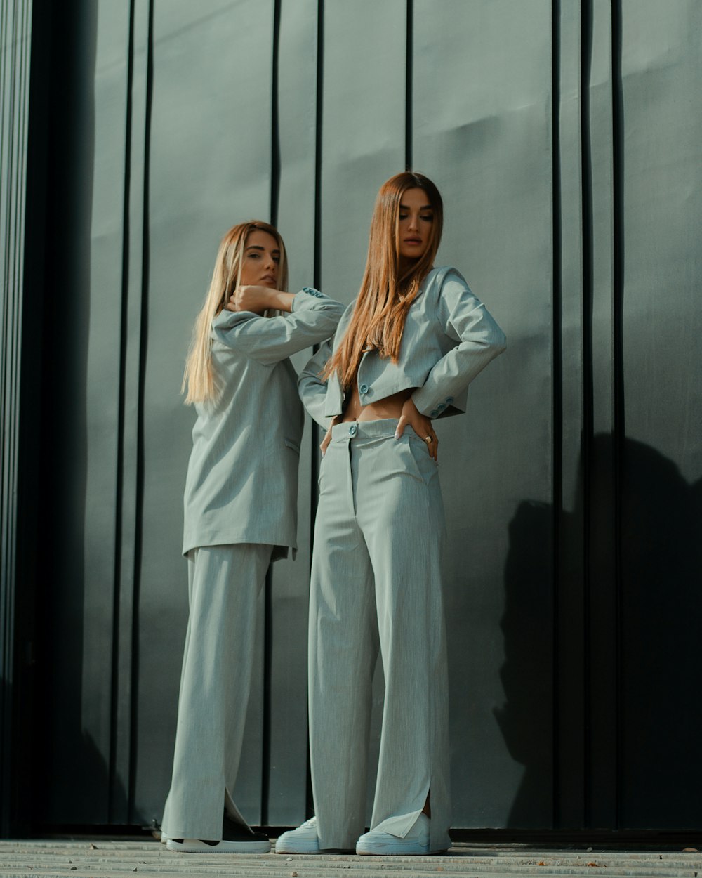 2 women in white long sleeve shirt standing beside glass window