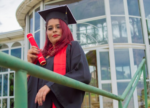 woman in academic gown holding red rose