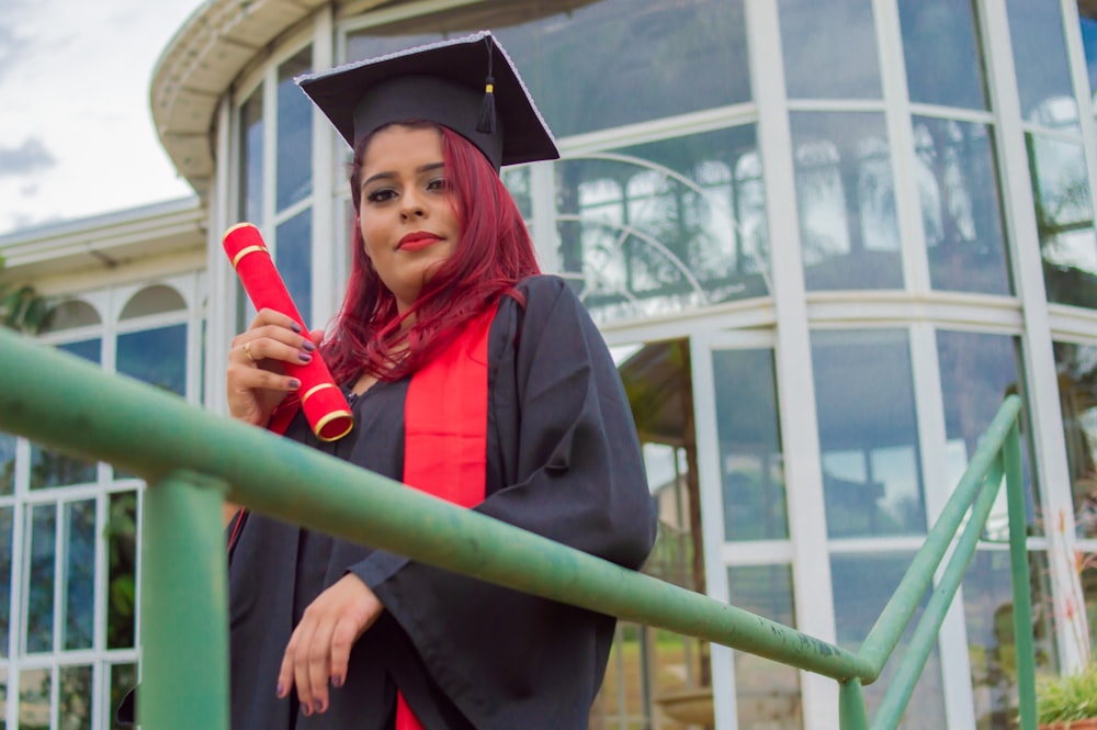 woman in academic gown holding red rose