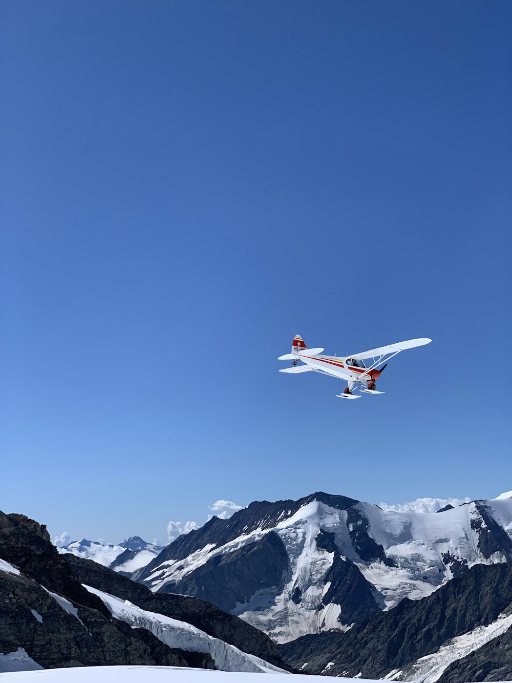 white and red airplane flying over snow covered mountain during daytime