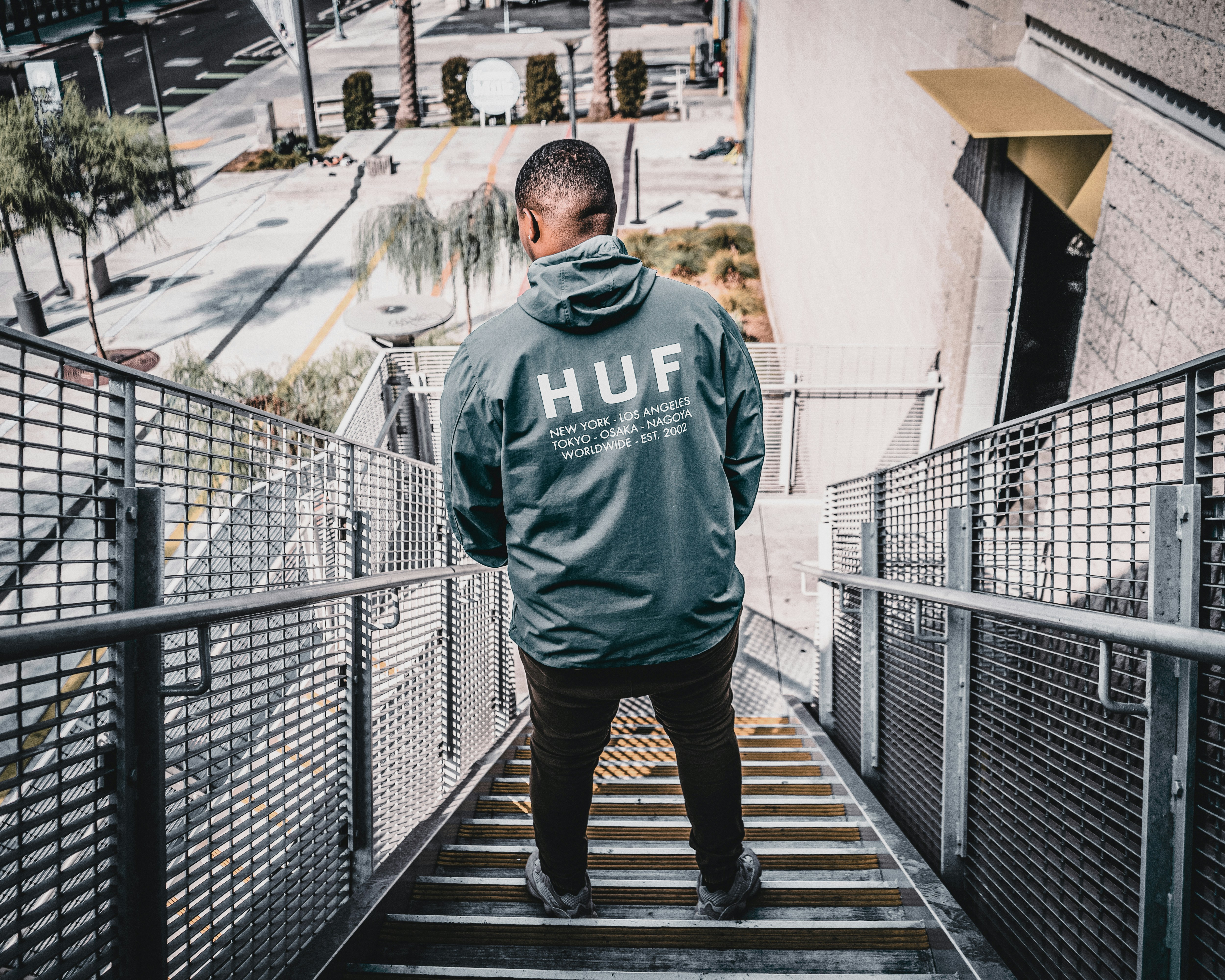 man in gray and black adidas hoodie standing on bridge during daytime