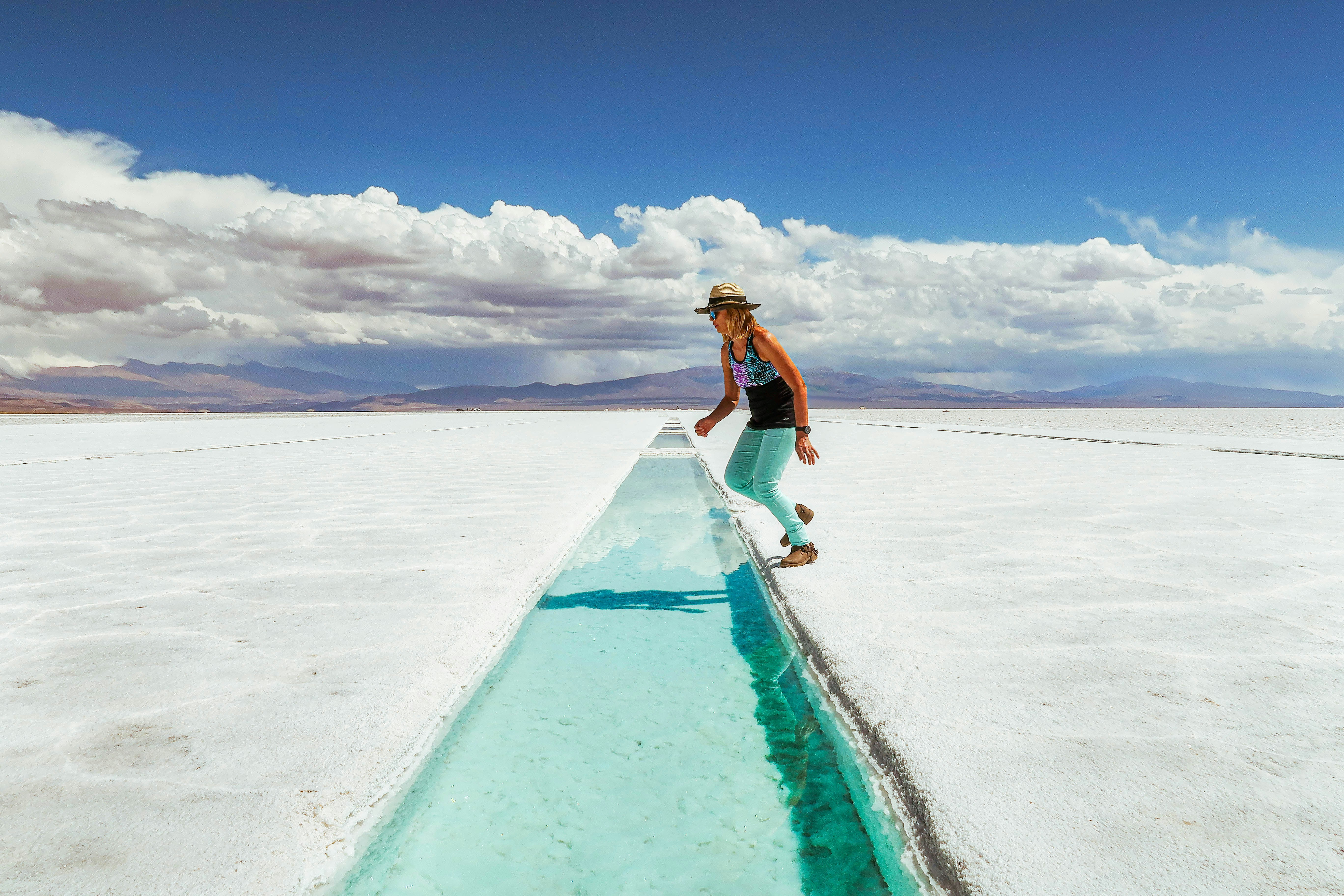 woman in black tank top and blue denim jeans standing on snow covered field under blue