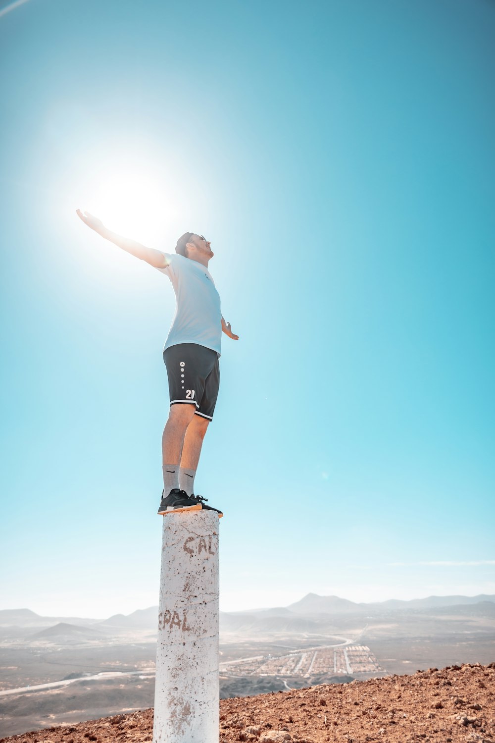 woman in black shorts jumping on brown rock during daytime