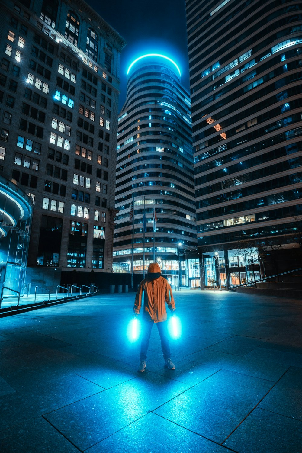 Mujer con abrigo naranja de pie frente a un edificio de gran altura