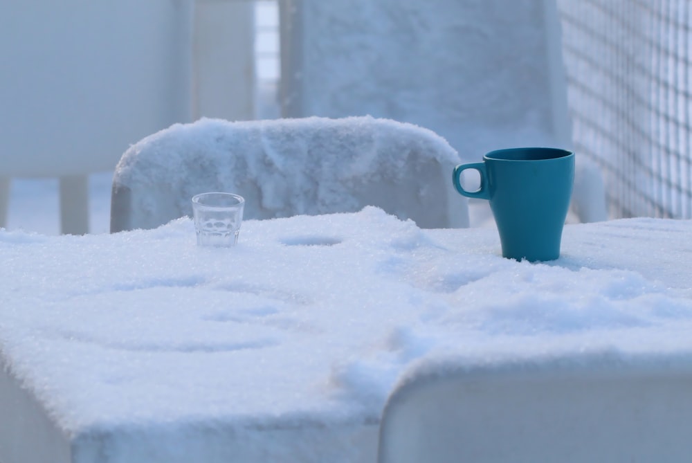 blauer Keramikbecher auf schneebedecktem Boden