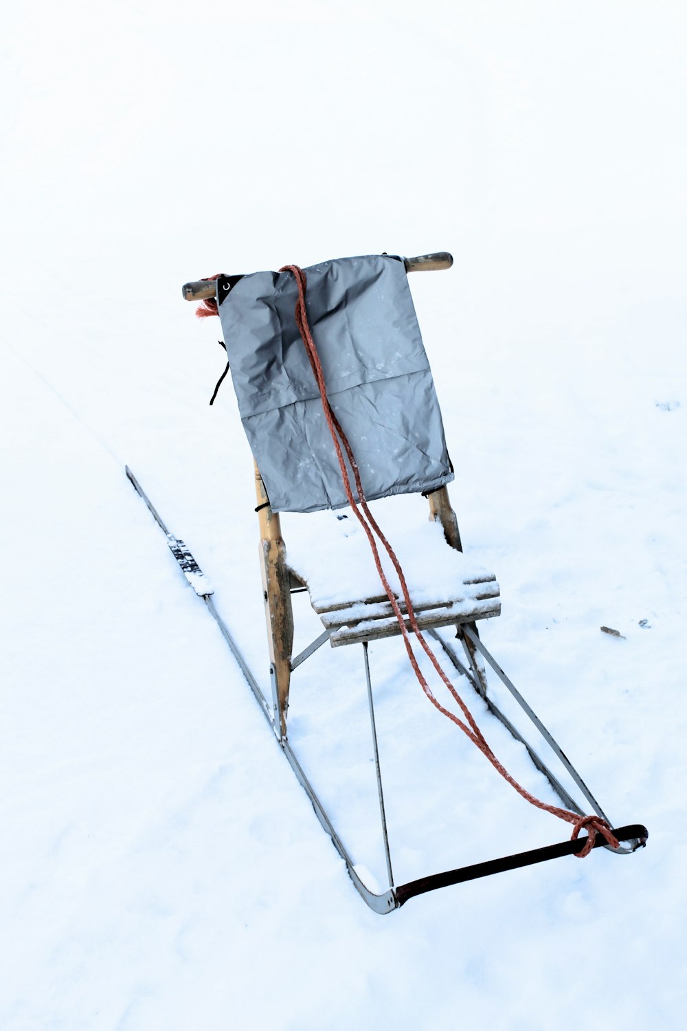 Persona in giacca grigia e pantaloni neri in piedi su terreno coperto di neve durante il giorno