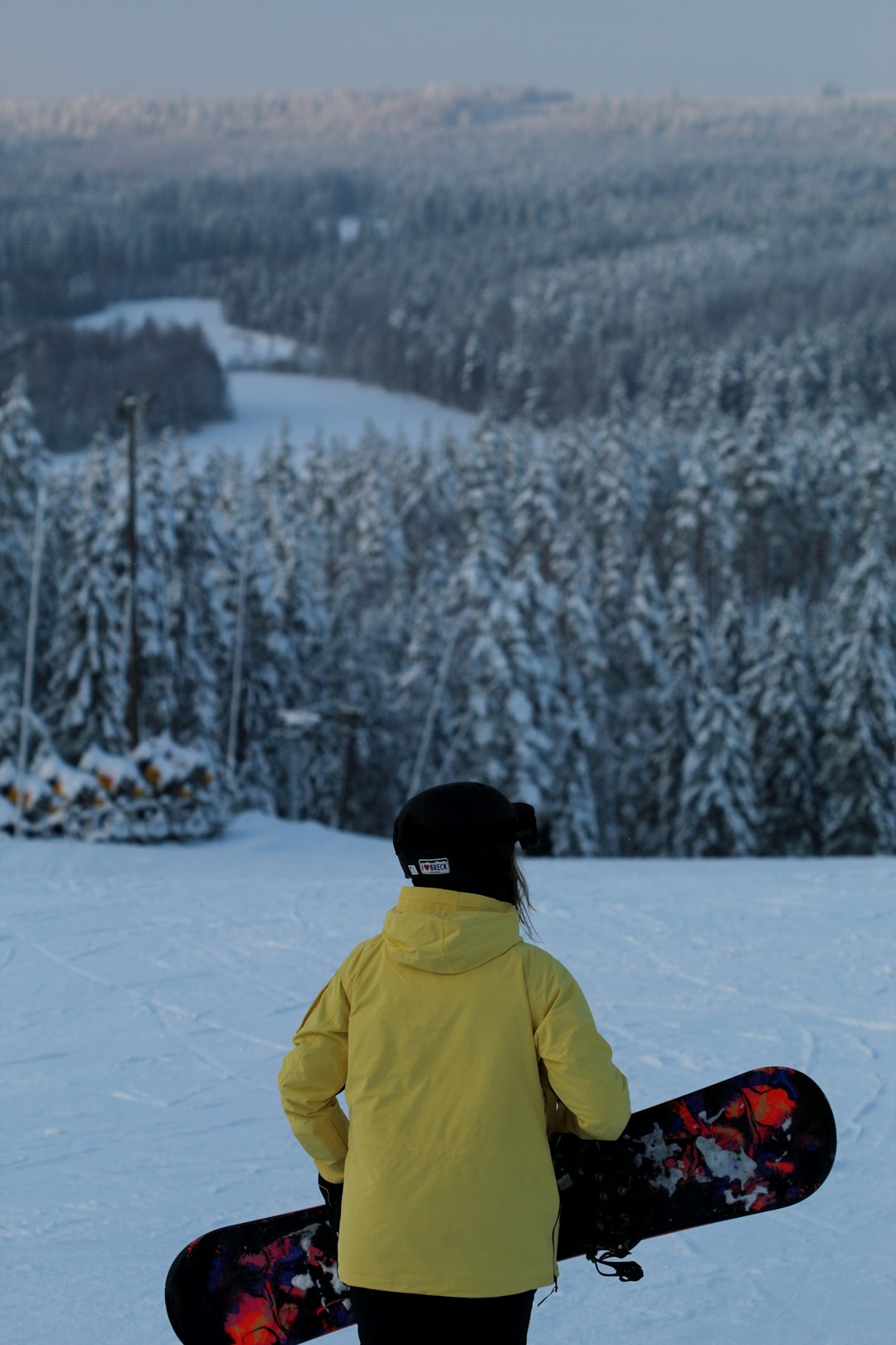 person in green jacket and black knit cap sitting on snow covered ground during daytime