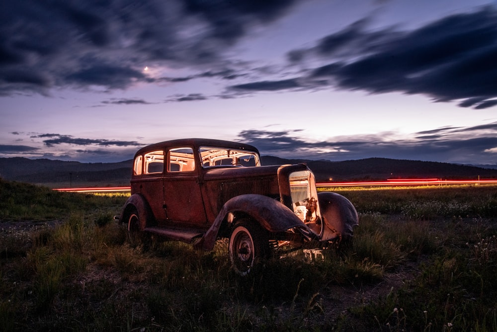 brown vintage car on green grass field under cloudy sky during daytime