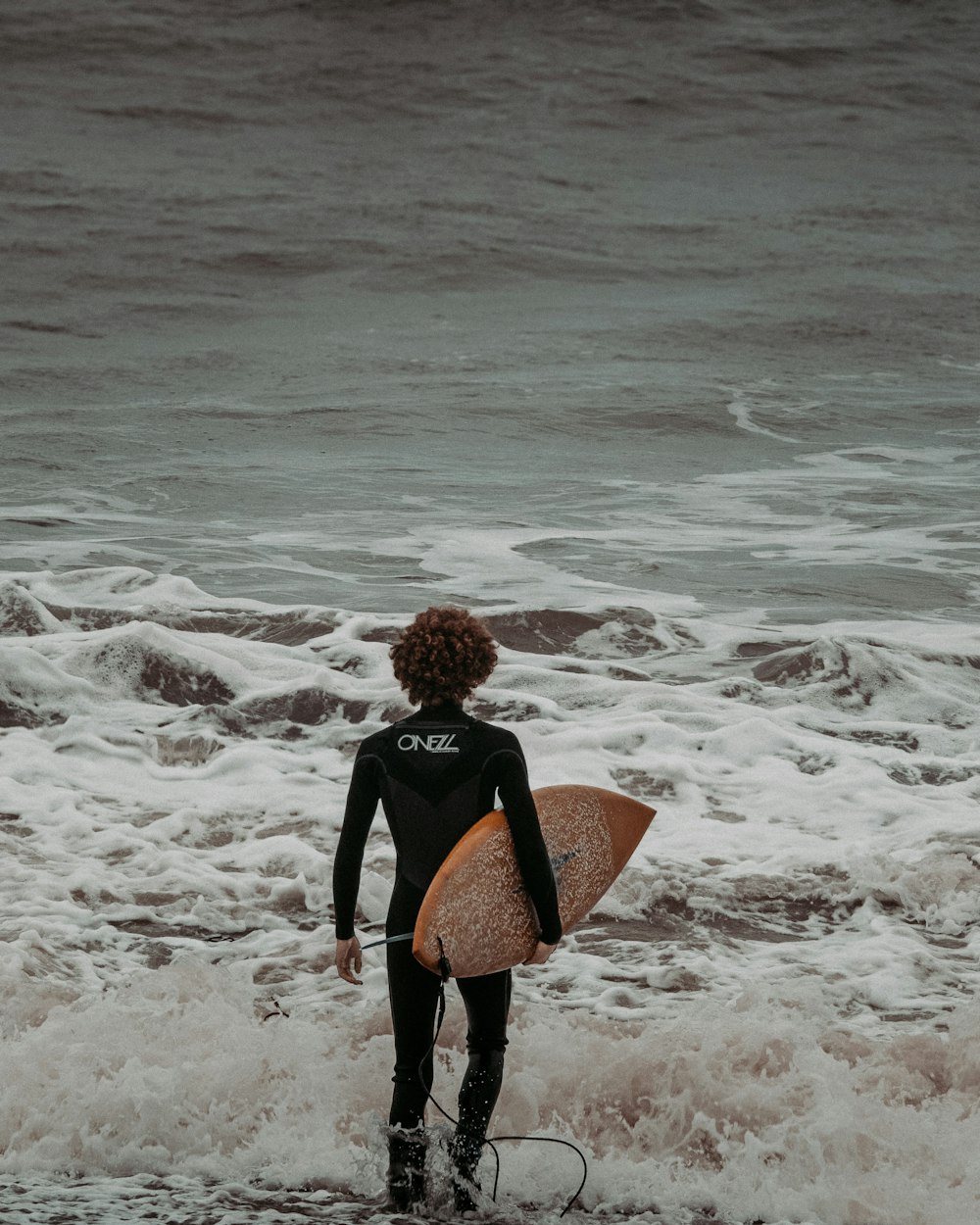 woman in black long sleeve shirt carrying brown and black backpack walking on beach during daytime