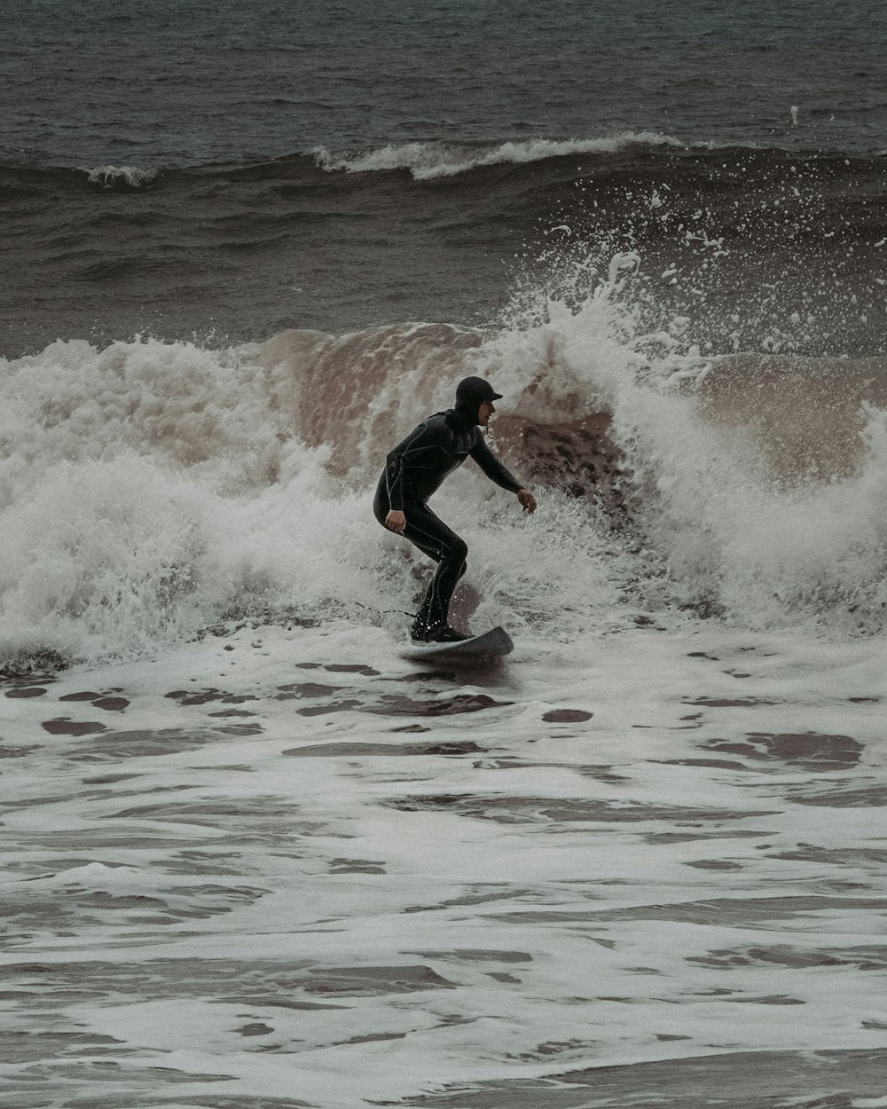 man in black wet suit surfing on sea waves during daytime