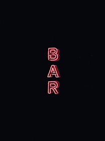 A neon sign displays the word 'BAR' in bold, red capital letters against a dark background.