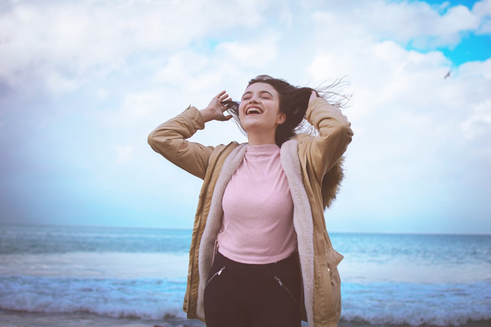 woman in pink long sleeve shirt and black pants standing on beach during daytime