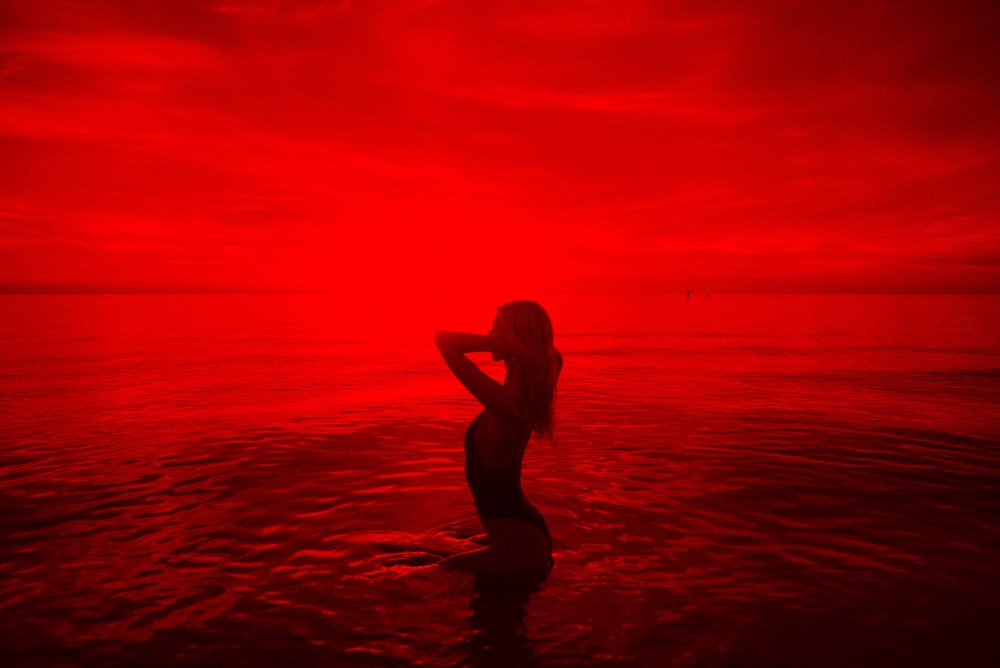 Mujer en bikini negro caminando en la playa durante la puesta del sol