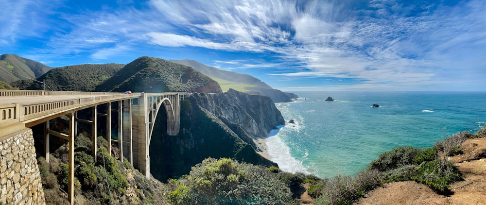 montanha verde e marrom ao lado do corpo de água sob o céu azul durante o dia