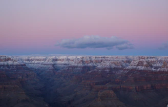Winter snow dusting the rocky edges of the canyon, with steam rising from hot springs below under a clear blue sky.