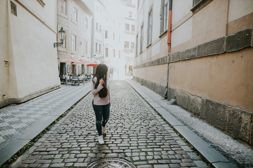 woman in black pants walking on sidewalk during daytime