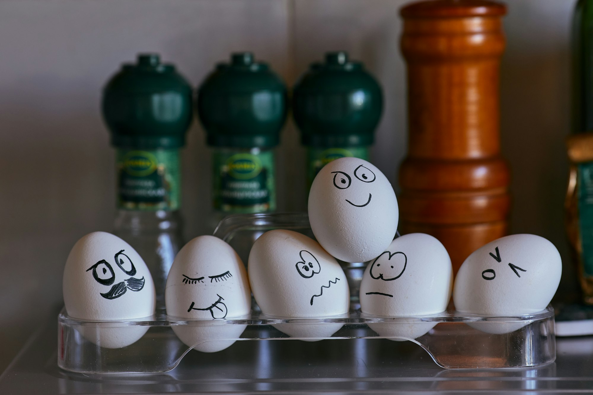 Emotional background with eggs and condiments in the kitchen. Painted faces on eggs for Easter. Emotions, smiles, mouths and eyes on chicken eggs