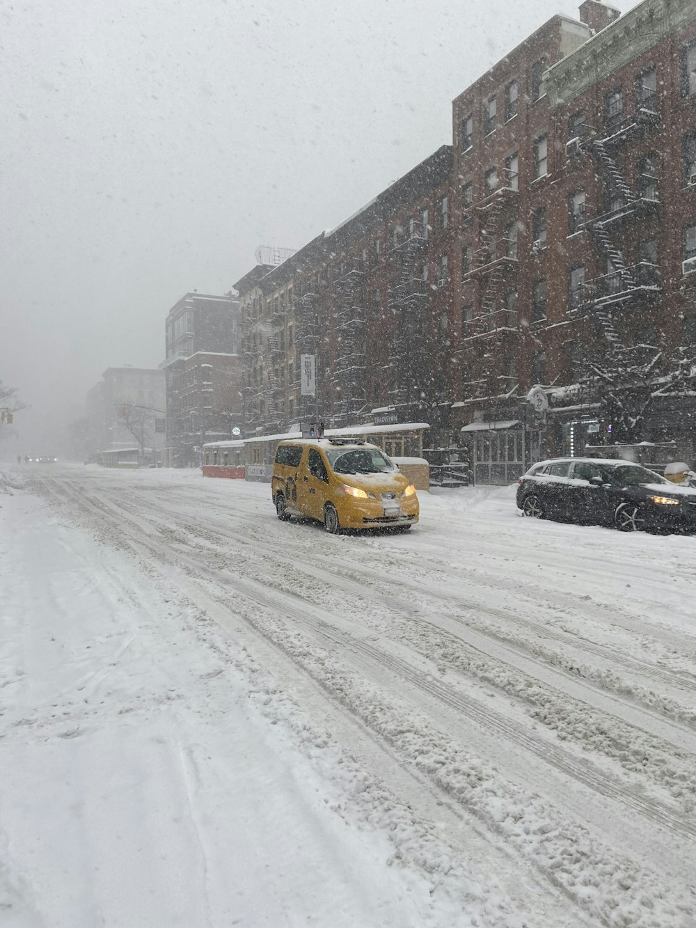 yellow taxi cab on snow covered road near brown concrete building during daytime