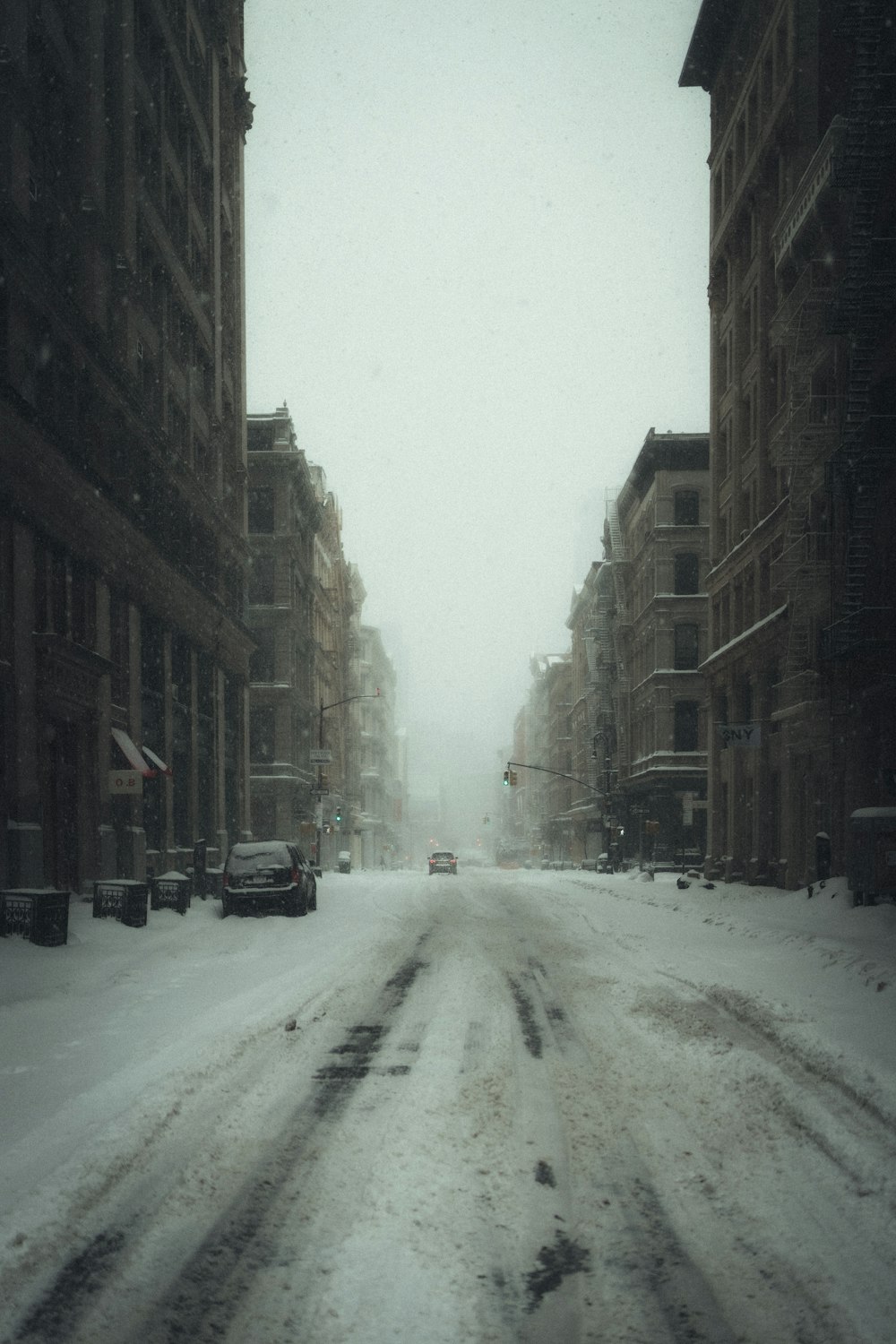 snow covered road between buildings during daytime