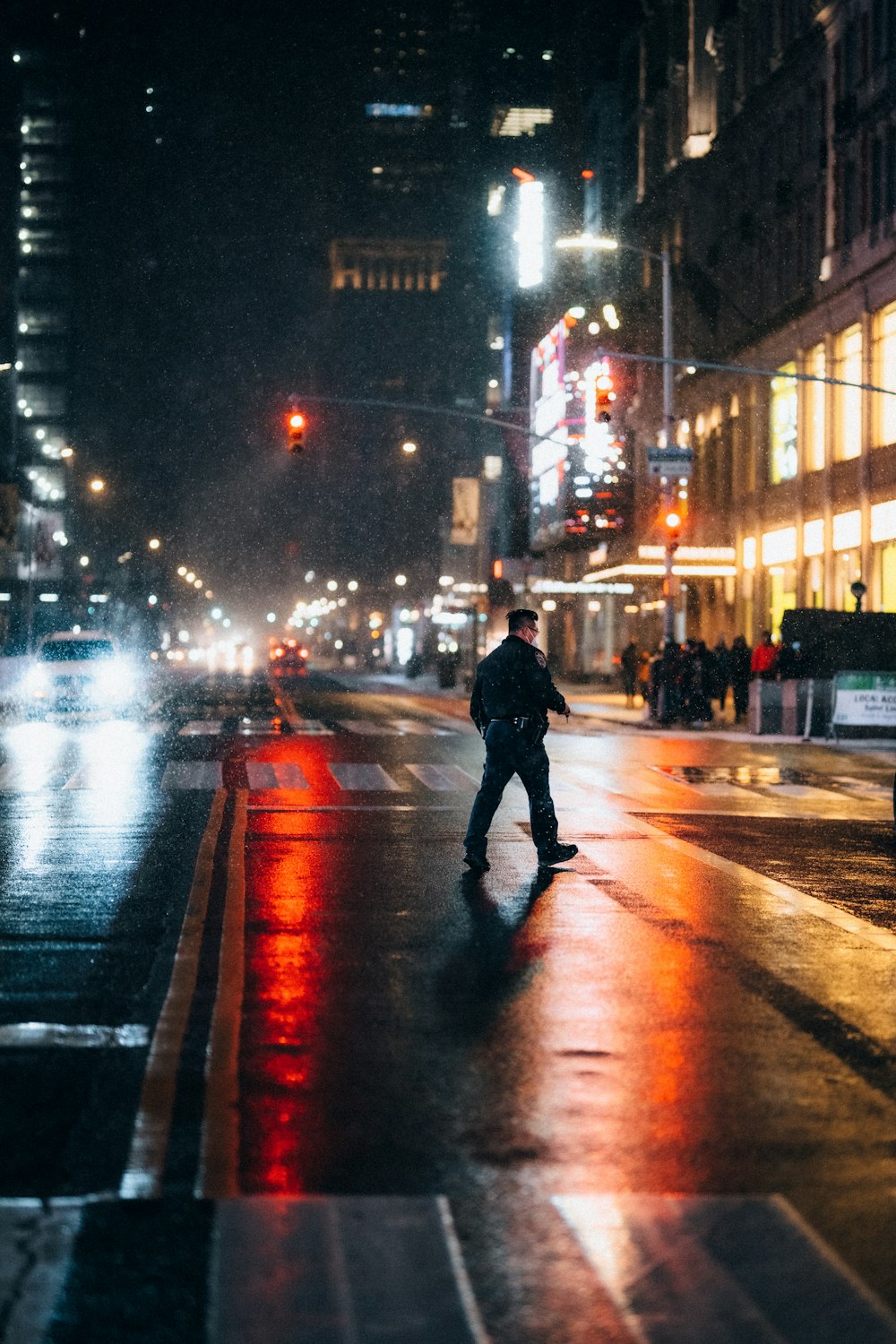 man in black jacket walking on sidewalk during night time