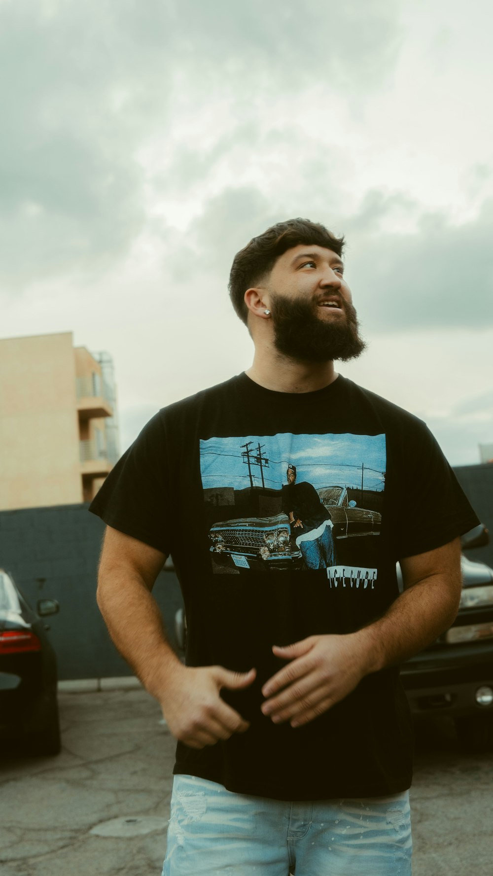 man in black crew neck t-shirt standing near red car during daytime