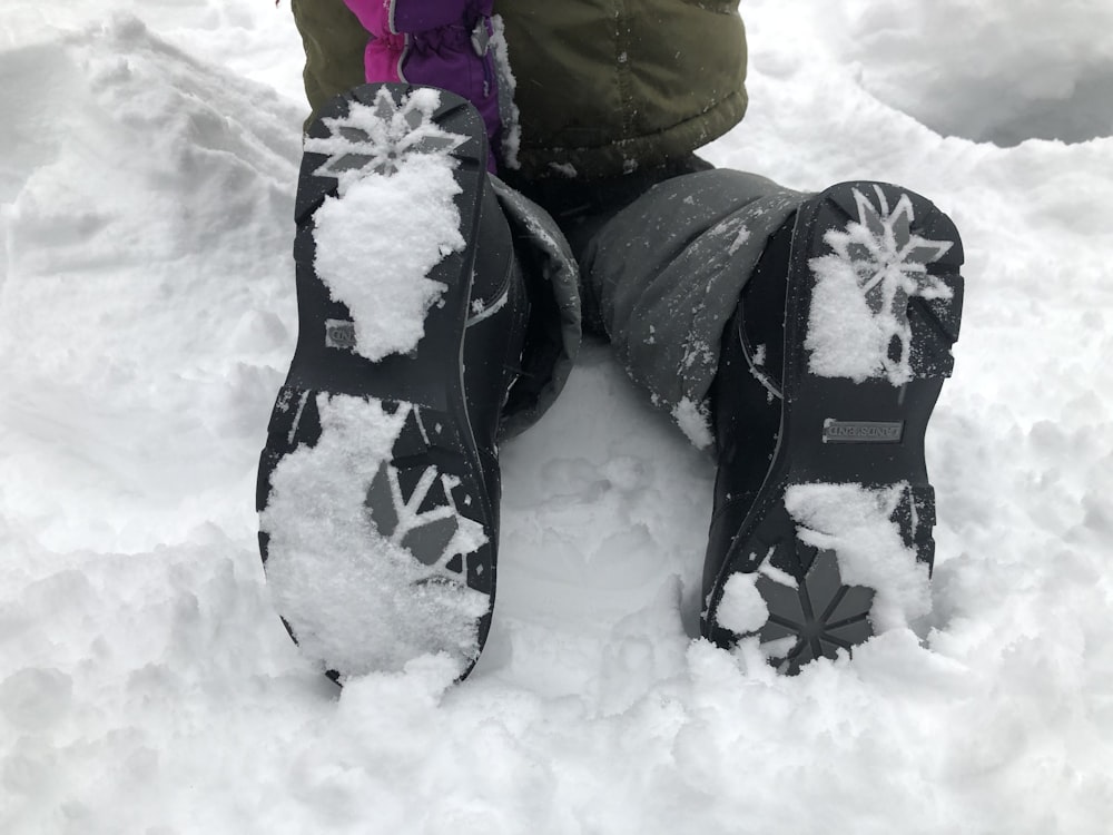 person in yellow jacket and black pants sitting on snow covered ground