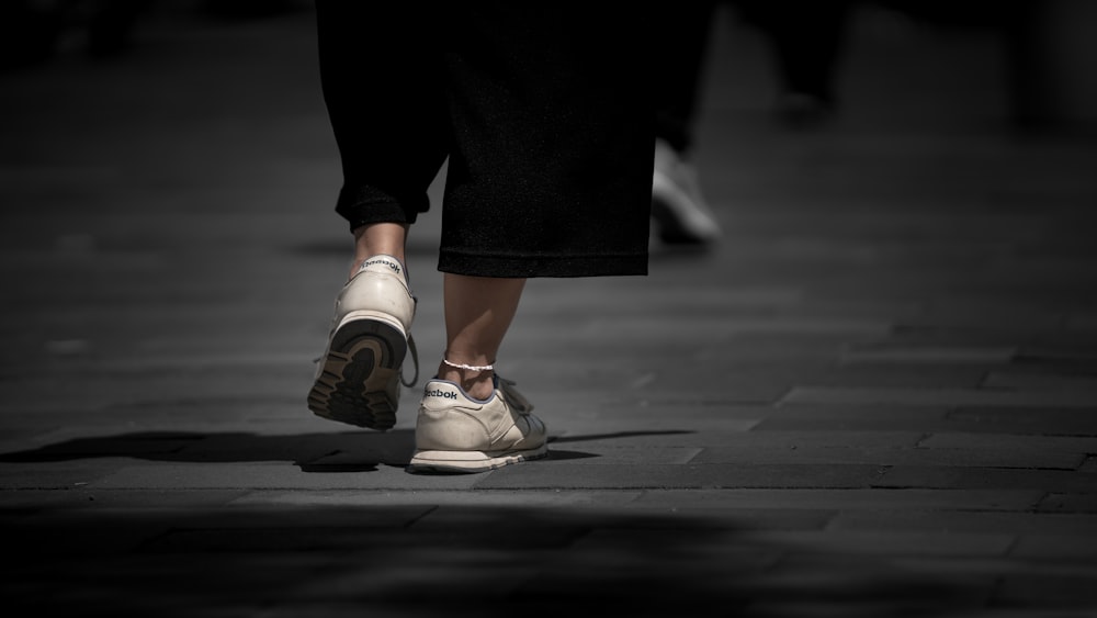 person in black pants and white and orange nike sneakers