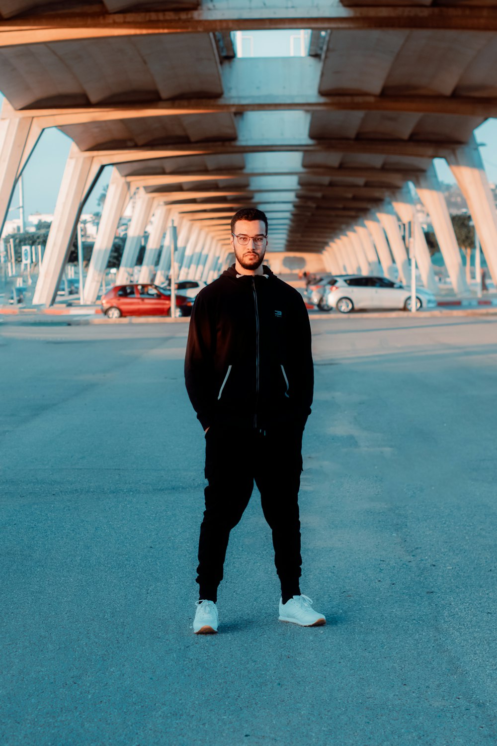 man in black jacket standing on gray asphalt road during daytime