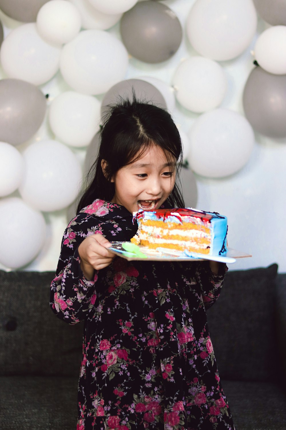 girl in black and pink floral long sleeve shirt holding cake