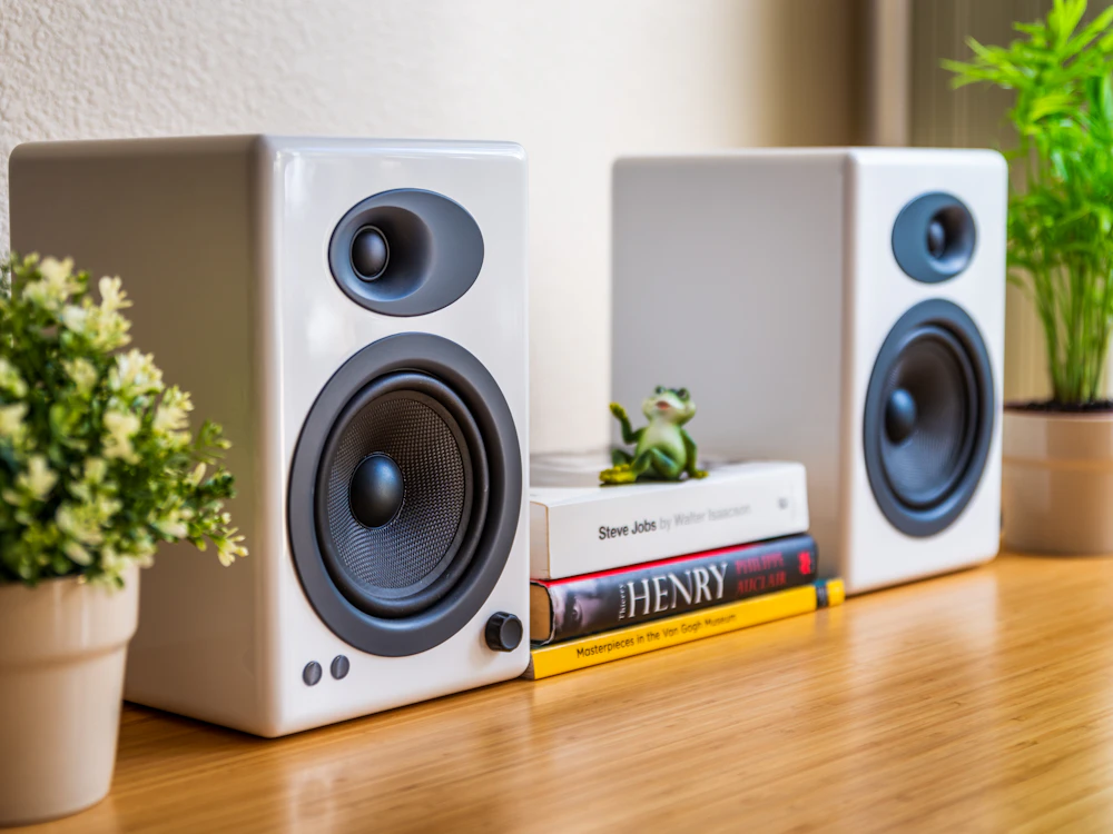 Pair of white bookshelf speakers on a wooden desk