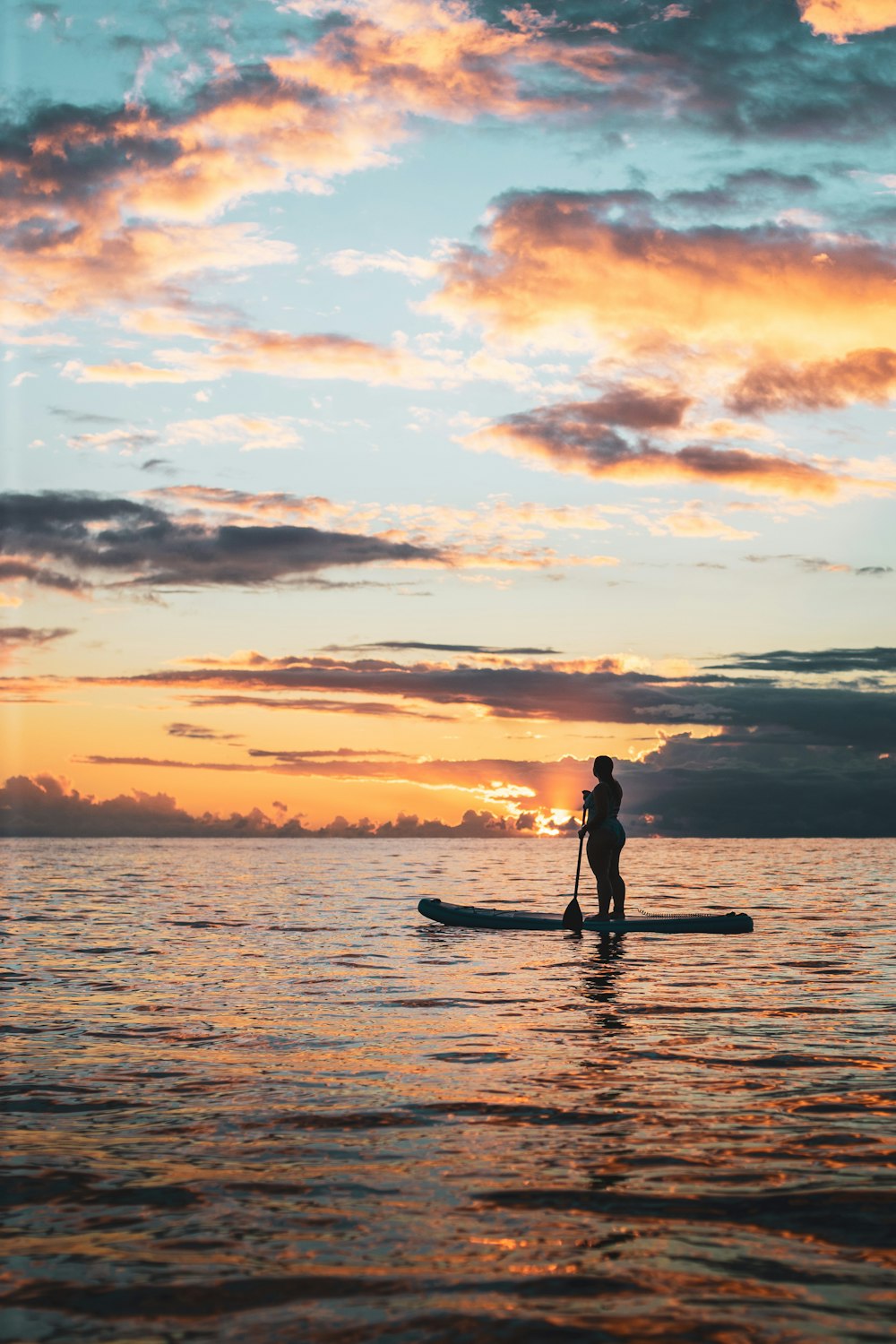 man in black wet suit riding on surfboard during sunset