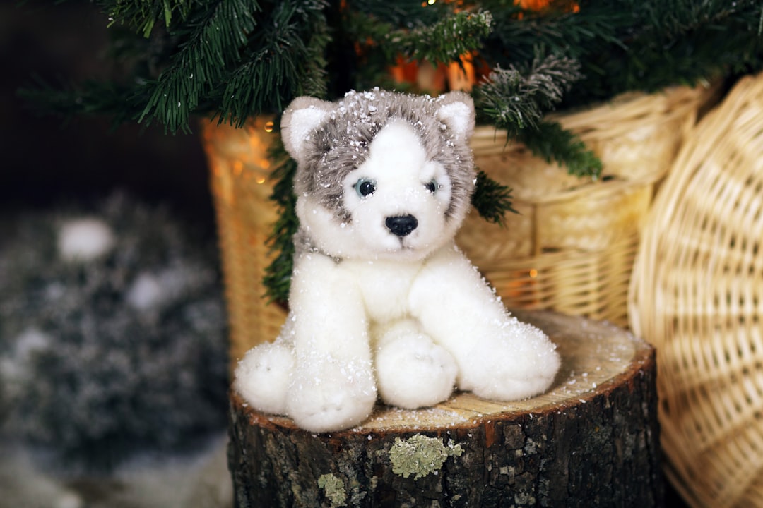 white and black panda bear plush toy on brown wooden log