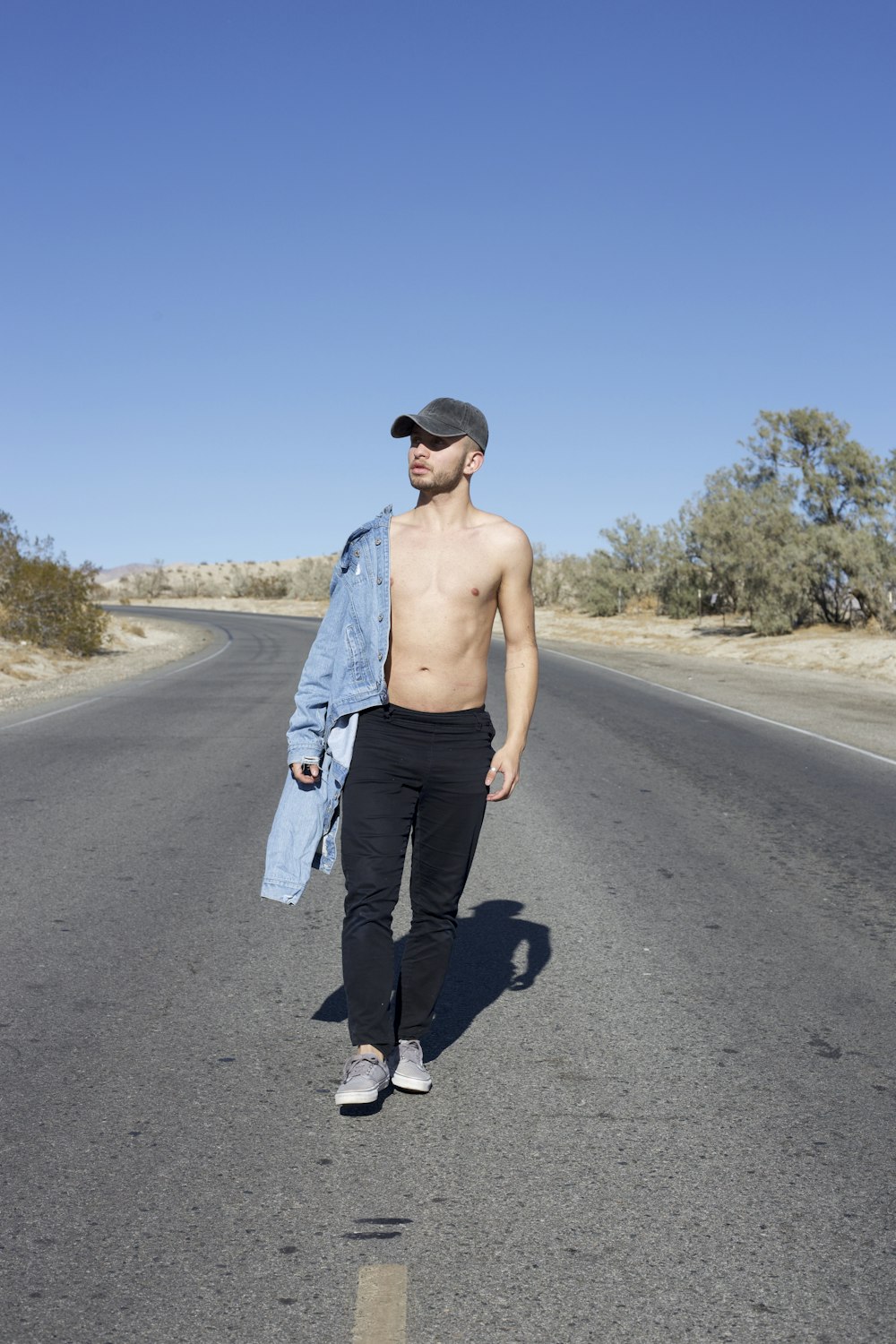 a shirtless man walking down the middle of a road