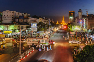 Cityscape of Phnom Penh showcasing diverse advertising billboards lit up at dusk.