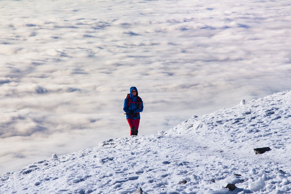 person in black jacket and blue denim jeans standing on snow covered ground during daytime