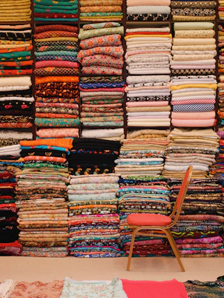 telas de diferentes colores dobladas una encima de la otra y una silla roja