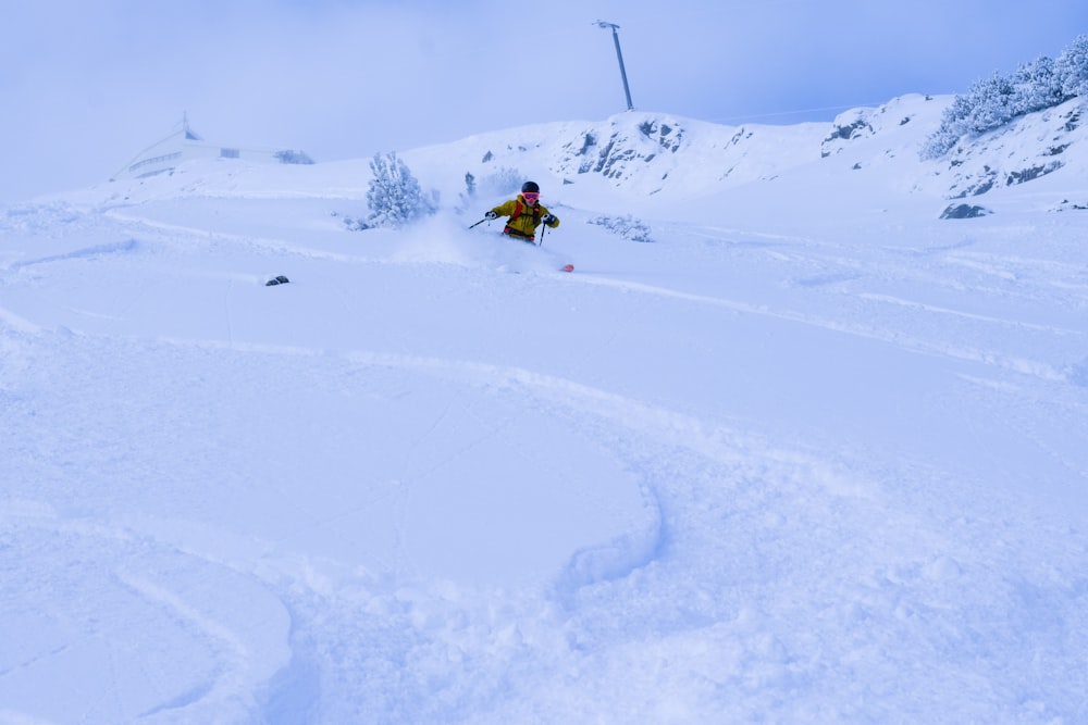 person in yellow jacket riding on snow board on snow covered ground during daytime