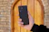 A happy customer holding a smartphone next to the installed smart lock on a front door.