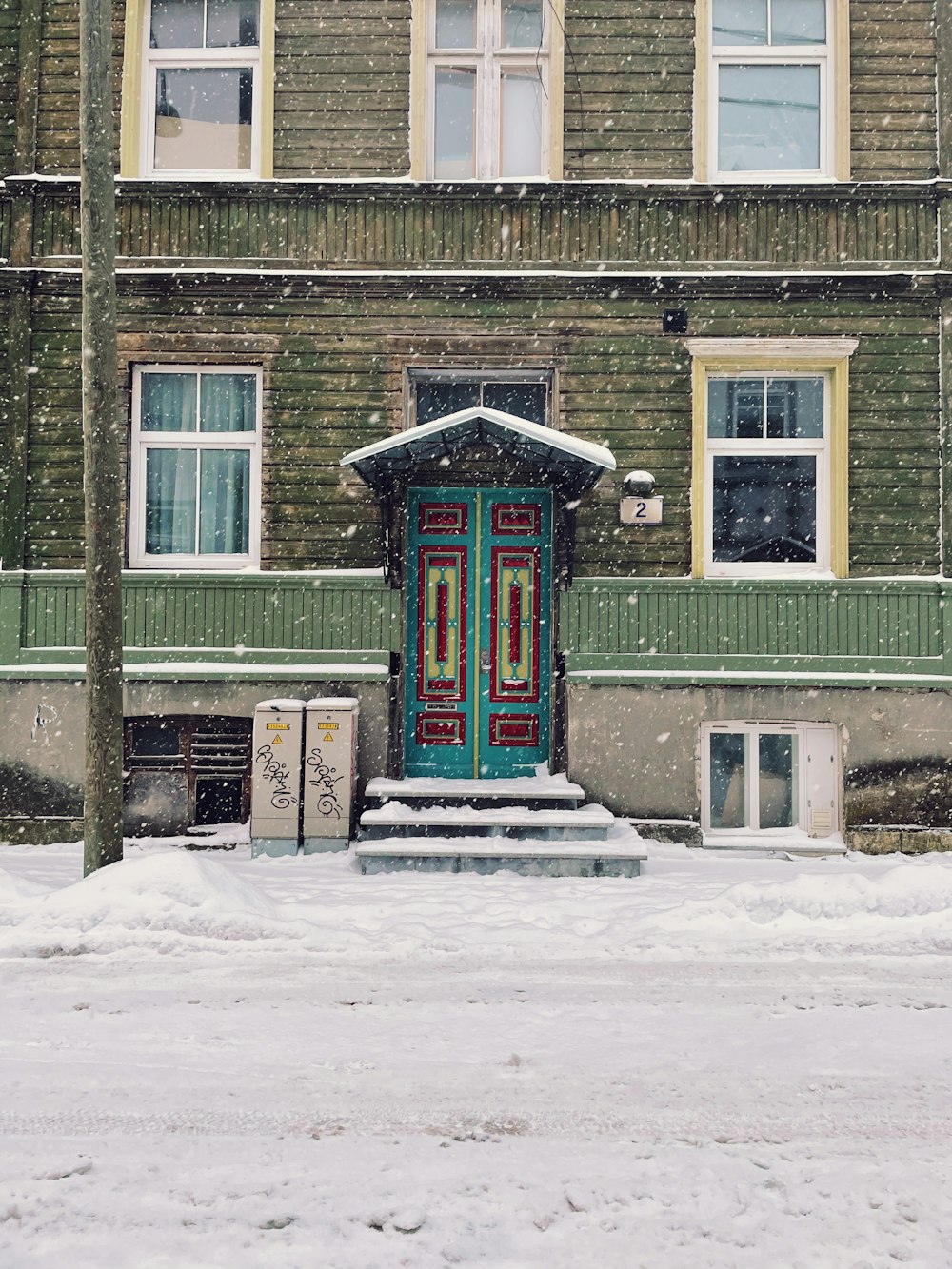 Maison en bois vert et blanc recouverte de neige