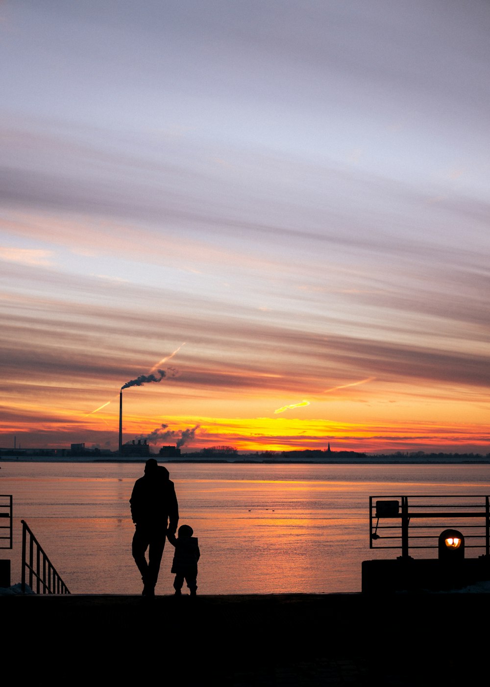 silhouette of man and woman standing on dock during sunset