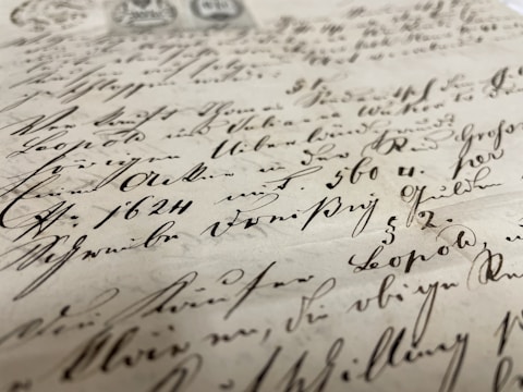 A close-up view of an antique manuscript with elegant handwritten text. The ink is dark and appears slightly faded with time, written on aged, yellowed paper. The script is flowing and ornate, indicative of a historical document.