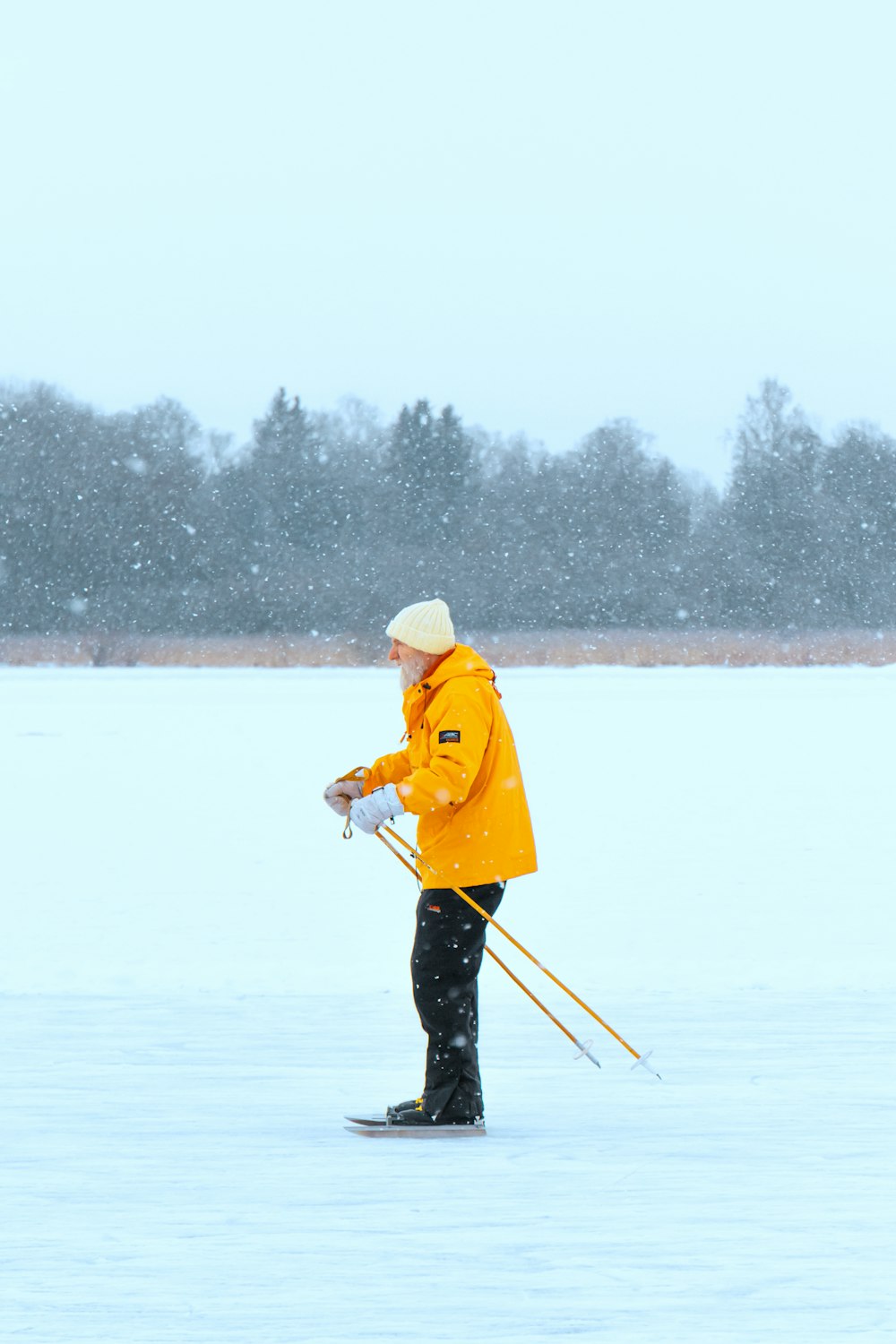 man in yellow jacket and black pants holding yellow stick on snow covered ground during daytime
